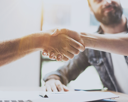 People shaking hands over a conference room table